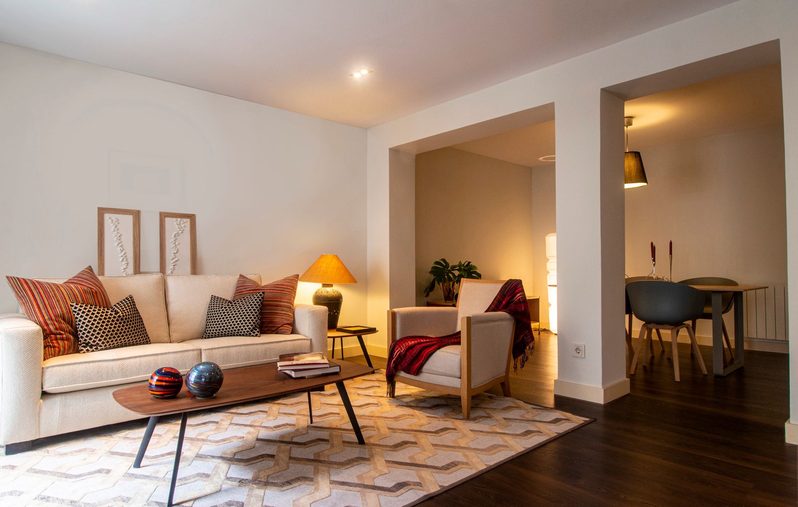 A cosy, warmly lit living room with a soft sofa and considered, lived-in styling