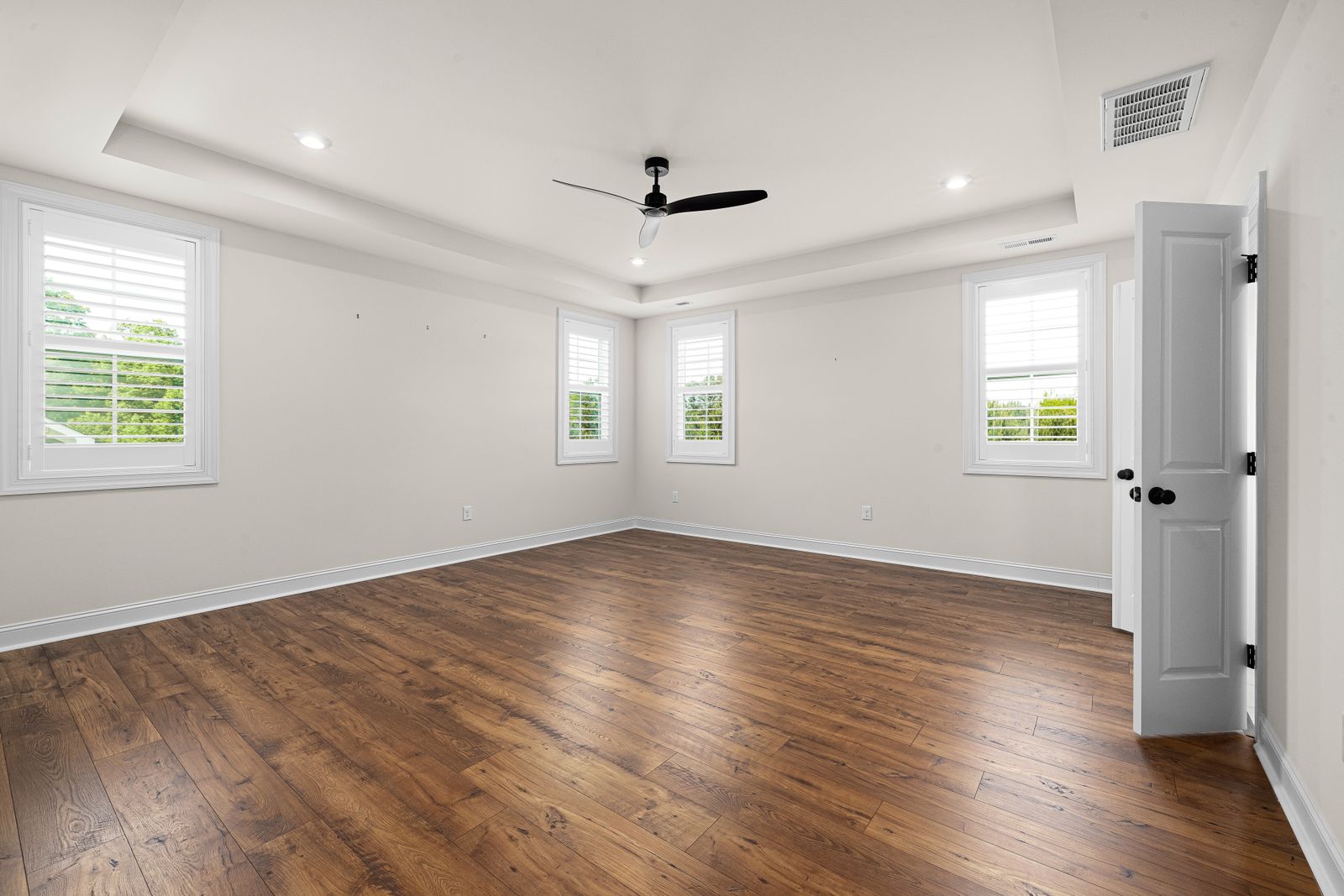 An empty room with white walls and warm wooden floors, waiting to be designed